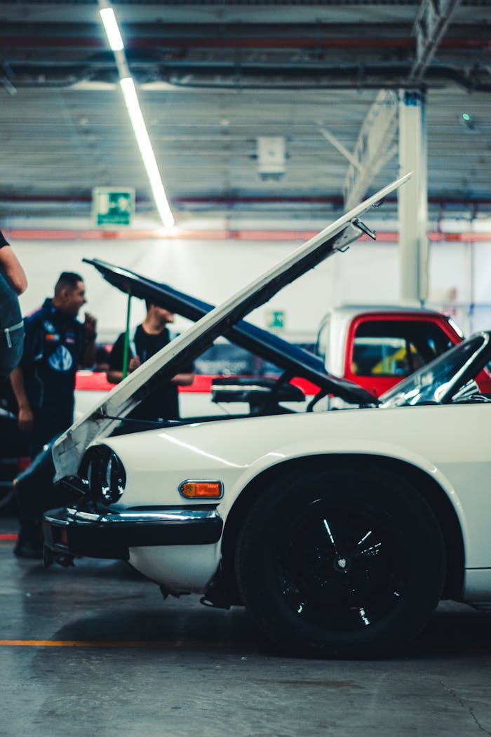 Classic car with open hood in a workshop, showcasing mechanical work and vehicle maintenance.